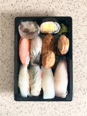 Çeşitli malzemeler ve canlı renklerle sanatsal olarak düzenlenmiş taze suşi çeşitleri. Bu geleneksel Japon yemeği bir deneyim için sirkeli pirinç, deniz ürünleri ve sebzeleri birleştirir..