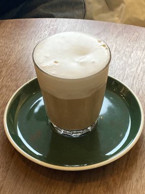 Çok güzel işlenmiş bir latte, kremalı köpüklü sanat eseri ve üstüne de espresso. Kahveyle ilgili projeler için mükemmel. Bu görüntü, klasik bir kafe deneyiminin sıcaklığını ve davetkar doğasını yansıtıyor..