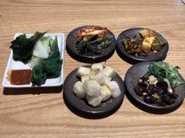 İçinde kimchi, baharatlı sebze, turp turşusu ve marine edilmiş yosun bulunan renkli bir banchan çeşidi. Bu Kore mezeleri masaya çeşitli dokular ve tatlar getiriyor..