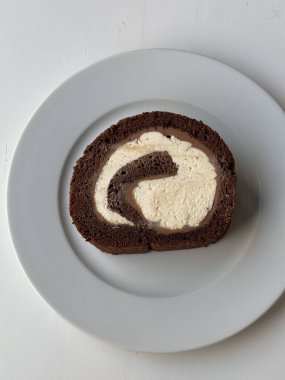 Yumuşak rulo pasta, yumuşacık sünger katmanları ve içi kremsi dolgulu. İçi pürüzsüz dokular, narin şekiller ve tatlı davetkar bir görünüm sergiliyor.