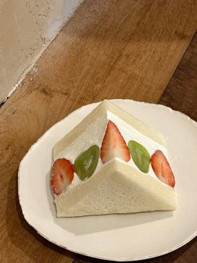 Tüylü beyaz ekmek, taze krema ve çilek, kivi ve mango gibi mevsimsel meyve dilimleri ile Japon meyve sandosu. Ferahlatıcı, renkli bir ikram. Her durum için mükemmel..