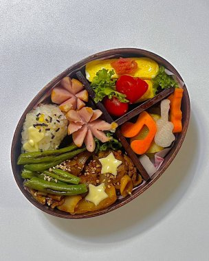 Geleneksel bir Kore dozirak 'ı. Pirinç, çeşitli banchan ve tuzlu proteinlerle güzelce düzenlenmiş. Dengeli ve görsel olarak davetkâr, canlı lezzetlerle dolu taşınabilir bir yemek..