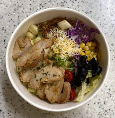 Taze salata taze yapraklı sebzeler, dilimlenmiş sebzeler ve rengarenk malzemelerin karışımı sağlıklı, canlı ve ferahlatıcı bir tat yaratmak için bir araya getirilmiş.