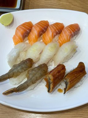 Çeşitli malzemeler ve canlı renklerle sanatsal olarak düzenlenmiş taze suşi çeşitleri. Bu geleneksel Japon yemeği bir deneyim için sirkeli pirinç, deniz ürünleri ve sebzeleri birleştirir..