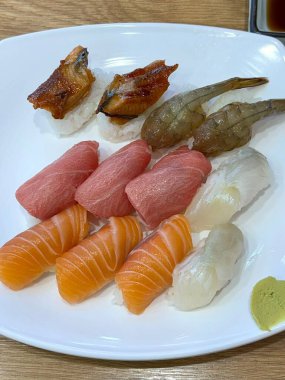 Çeşitli malzemeler ve canlı renklerle sanatsal olarak düzenlenmiş taze suşi çeşitleri. Bu geleneksel Japon yemeği bir deneyim için sirkeli pirinç, deniz ürünleri ve sebzeleri birleştirir..