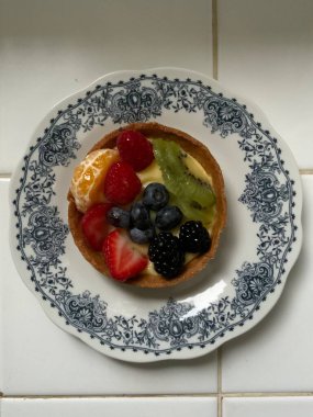 Tereyağlı, kremalı kremayla dolu ve üzerinde taze, canlı meyveler olan lezzetli bir meyveli tart. Tatlı ve keskin arasında mükemmel bir denge, onu karşı konulamaz kılıyor.