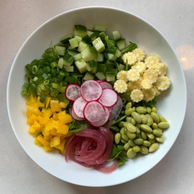 Taze salata taze yapraklı sebzeler, dilimlenmiş sebzeler ve rengarenk malzemelerin karışımı sağlıklı, canlı ve ferahlatıcı bir tat yaratmak için bir araya getirilmiş.