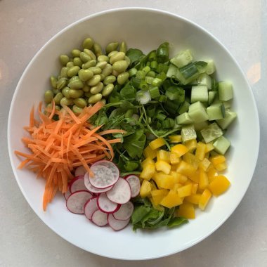 Taze salata taze yapraklı sebzeler, dilimlenmiş sebzeler ve rengarenk malzemelerin karışımı sağlıklı, canlı ve ferahlatıcı bir tat yaratmak için bir araya getirilmiş.