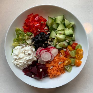 Taze salata taze yapraklı sebzeler, dilimlenmiş sebzeler ve rengarenk malzemelerin karışımı sağlıklı, canlı ve ferahlatıcı bir tat yaratmak için bir araya getirilmiş.