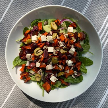 Taze salata taze yapraklı sebzeler, dilimlenmiş sebzeler ve rengarenk malzemelerin karışımı sağlıklı, canlı ve ferahlatıcı bir tat yaratmak için bir araya getirilmiş.