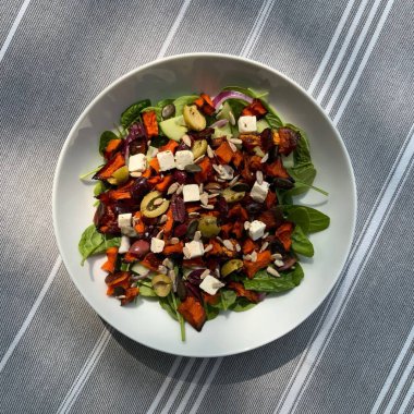 Taze salata taze yapraklı sebzeler, dilimlenmiş sebzeler ve rengarenk malzemelerin karışımı sağlıklı, canlı ve ferahlatıcı bir tat yaratmak için bir araya getirilmiş.