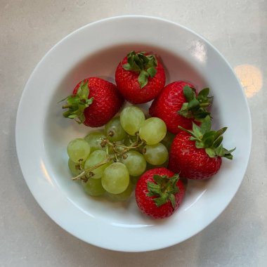 Taze çilekler ve parlak Muscat üzümleri kırmızı ve yeşilin canlı bir karışımını oluşturur. Sulu, tatlı ve görsel olarak çarpıcı, ferahlatıcı ikramlara ve renkli yiyeceklere çok uygun..
