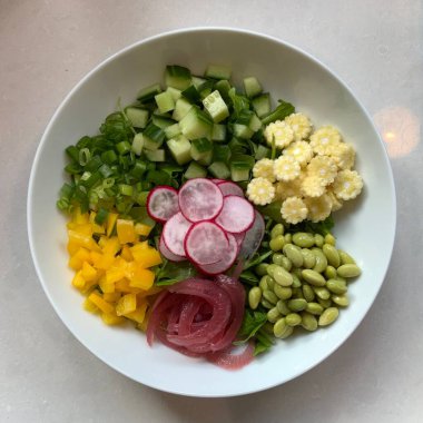 Taze salata taze yapraklı sebzeler, dilimlenmiş sebzeler ve rengarenk malzemelerin karışımı sağlıklı, canlı ve ferahlatıcı bir tat yaratmak için bir araya getirilmiş.