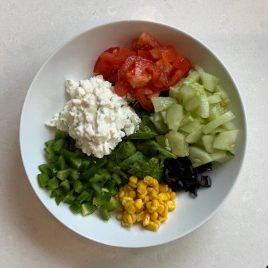 Taze salata taze yapraklı sebzeler, dilimlenmiş sebzeler ve rengarenk malzemelerin karışımı sağlıklı, canlı ve ferahlatıcı bir tat yaratmak için bir araya getirilmiş.