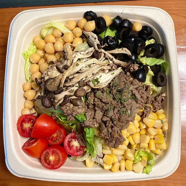 Taze salata taze yapraklı sebzeler, dilimlenmiş sebzeler ve rengarenk malzemelerin karışımı sağlıklı, canlı ve ferahlatıcı bir tat yaratmak için bir araya getirilmiş.