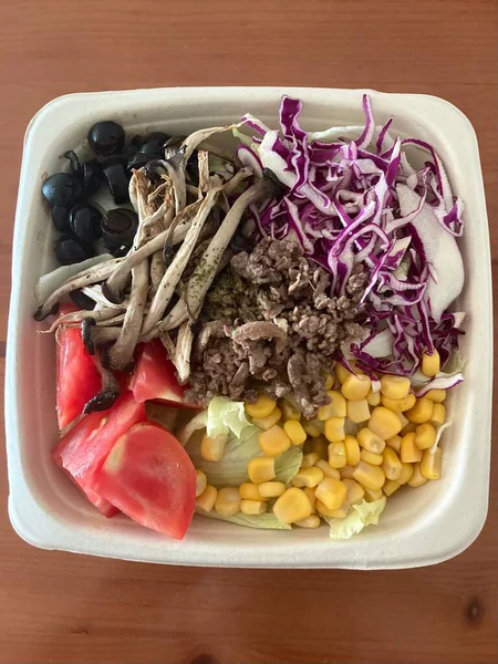 Taze salata taze yapraklı sebzeler, dilimlenmiş sebzeler ve rengarenk malzemelerin karışımı sağlıklı, canlı ve ferahlatıcı bir tat yaratmak için bir araya getirilmiş.