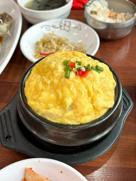 Steamed Korean egg dish, Gyeran Jjim, known for its light, fluffy texture. Served hot, often in an earthenware pot, this savory and comforting dish pairs well with rice and banchan.