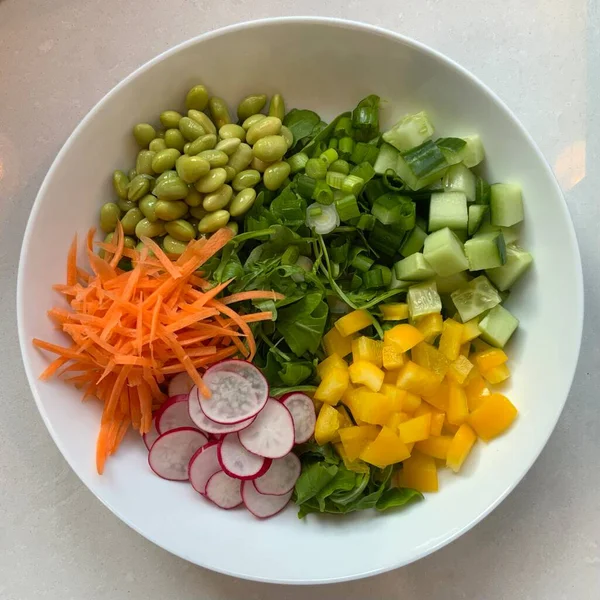 Taze salata taze yapraklı sebzeler, dilimlenmiş sebzeler ve rengarenk malzemelerin karışımı sağlıklı, canlı ve ferahlatıcı bir tat yaratmak için bir araya getirilmiş.