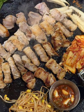 Izgara samgyeopsal, ızgarada pişen domuz eti dilimleri. Lezzetli bir yemek deneyiminin özünü yakalayan popüler bir Kore barbekü yemeği..