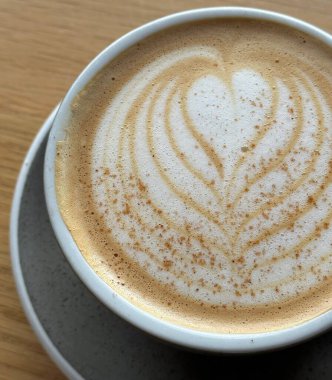 Çok güzel işlenmiş bir latte, kremalı köpüklü sanat eseri ve üstüne de espresso. Kahveyle ilgili projeler için mükemmel. Bu görüntü, klasik bir kafe deneyiminin sıcaklığını ve davetkar doğasını yansıtıyor..