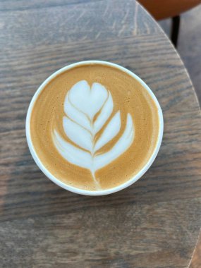 Çok güzel işlenmiş bir latte, kremalı köpüklü sanat eseri ve üstüne de espresso. Kahveyle ilgili projeler için mükemmel. Bu görüntü, klasik bir kafe deneyiminin sıcaklığını ve davetkar doğasını yansıtıyor..