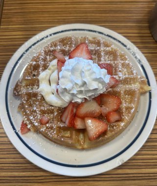 Üstünde bol kremalı vanilyalı dondurma ve çikolata sosu serpiştirilmiş çıtır altın waffle. Klasik, hoşgörülü bir tatlı..
