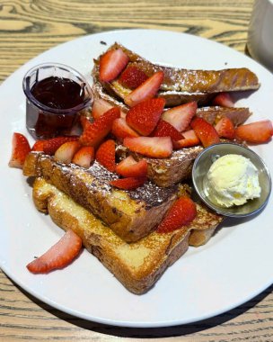 Üzerine taze çilek konmuş altın yumurtalı ekmek yumuşak, yumuşak bir dokuya ve yumuşak bir tatlılığa sahip. Sıcak, davetkar ve görsel olarak çekici. Sıcak kahvaltı ya da brunch anları için mükemmel..