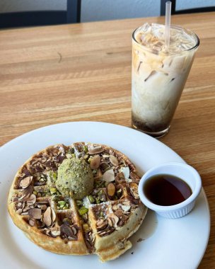 Üstünde bol kremalı vanilyalı dondurma ve çikolata sosu serpiştirilmiş çıtır altın waffle. Klasik, hoşgörülü bir tatlı..