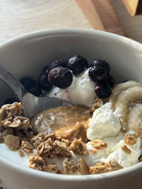 Taze meyve ve çıtır çıtır malzemelerle kaplı kremalı yoğurt kasesi pürüzsüz bir doku ve ferahlatıcı bir tat sunuyor. Hafif, sağlıklı ve görsel olarak çekici, kahvaltı ya da sağlıklı atıştırmalıklar için mükemmel..
