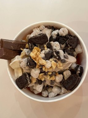 Taze meyve ve çıtır çıtır malzemelerle kaplı kremalı yoğurt kasesi pürüzsüz bir doku ve ferahlatıcı bir tat sunuyor. Hafif, sağlıklı ve görsel olarak çekici, kahvaltı ya da sağlıklı atıştırmalıklar için mükemmel..