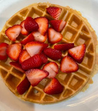 Üstünde bol kremalı vanilyalı dondurma ve çikolata sosu serpiştirilmiş çıtır altın waffle. Klasik, hoşgörülü bir tatlı..