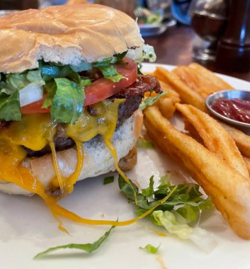Kızarmış patateslerin yanında taze malzemelerle servis edilen sulu bir hamburgerin klasik kombinasyonu. Lezzetli tatları ve çıtır çıtır dokuları harmanlayan doyurucu bir yemek için mükemmel..