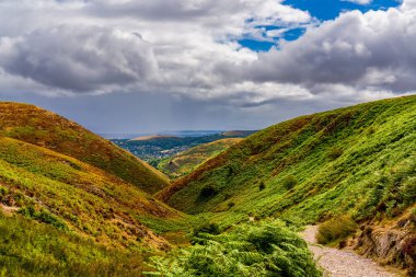 İngiliz Tepeleri 'ndeki dramatik Fırtına Bulutlarının Altındaki Güneş Vadisi Yolu