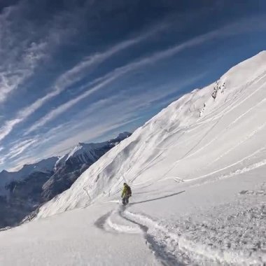 Sosyal medya için kare video. Canlı mavi gökyüzü altında dramatik bulutlar altında taze toz kullanan bir snowboardcunun dinamik bir görüntüsü..