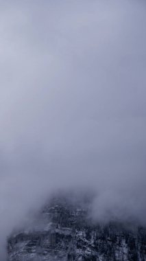 Karlı bir dağ uçurumunun kavramsal minimalist görüntüsü kısmen yoğun sisle gizlenmiş, yalnızlık, sessizlik ve yalnızlık hissi uyandırıyor.