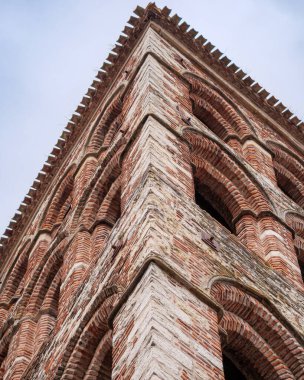 Alçak açı, tarihi bir çan kulesinin köşesine bakıyor. Alternatif kırmızı tuğla ve beyaz taş ustası..