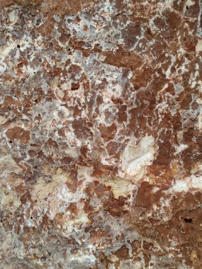 Yıpranmış bir taş yüzeyin detaylı bir yakın çekimi. Toprak bej, pas tonları, organik mineral lekeleri ve doğal dokular soyut, kırsal bir desen oluşturuyor..