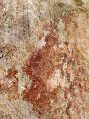 Yıpranmış bir taş yüzeyin detaylı bir yakın çekimi. Toprak bej, pas tonları, organik mineral lekeleri ve doğal dokular soyut, kırsal bir desen oluşturuyor..