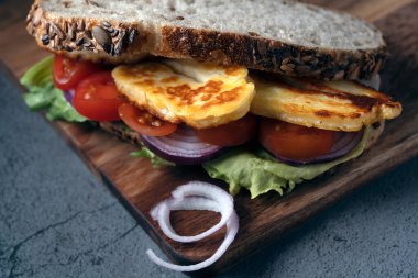 Izgara halloumi peyniri, taze vişneli domates, marul ve kıtır ekşi soğanlı lezzetli vejetaryen sandviçi.