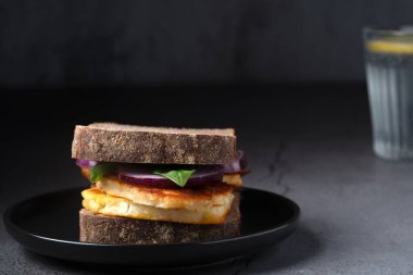 Vejetaryen öğle yemeğinde kızarmış halloumi peynirli sandviç ve bir bardak ferahlatıcı limonlu suyla servis ediliyor.