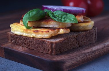 Sağlıklı atıştırmalıklar. Bir dilim koyu çavdar ekmeğinde ızgara halloumi peyniri ve aromatik fesleğen.