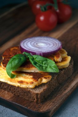 Kalın dilimli ızgara halloumi peyniri, kırmızı soğan ve taze fesleğen ile nefis, açık yüzlü sandviç.