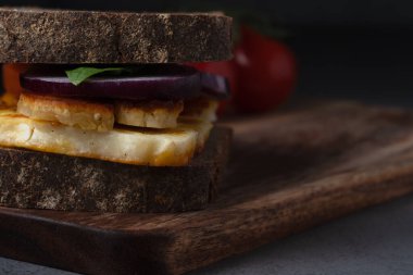 Lezzetli bir vejetaryen sandviçi ızgara halloumi peyniri, taze ıspanak ve tuzlu ekşi ekmeğin üzerine kırmızı soğan.