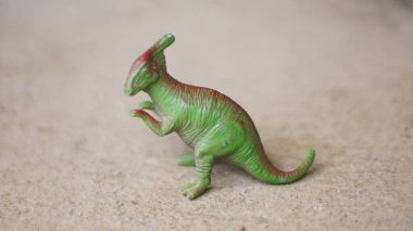 Beton zeminde minyatür yeşil Parasaurolophus dinozor oyuncak heykelciği. Yeşil Parasaurolophus biblosu Bokeh arkaplanına yakın