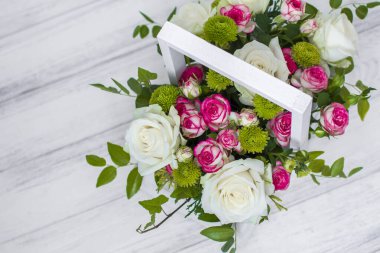 Beyaz ve pembe güller ve beyaz ahşap tahtada kasımpatılar olan tahta kutu. Evin dekorasyonu. Çiçek kutuları. Düğün süslemesi