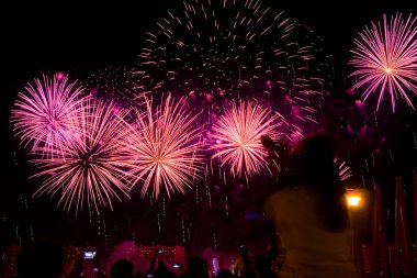 Akşam gökyüzünde güzel renkli havai fişekler. Seyirciler izliyor..