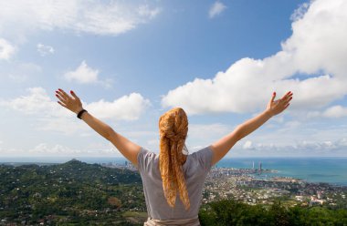 Kafasında eşarp olan narin bir genç kız kollarını Batumi şehrine doğru açtı. Georgia.