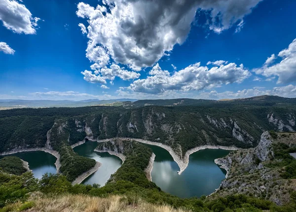 Orman tepeleri ve doğa gücünü ve özgürlüğünü temsil eden dramatik bulutlarla çevrili dolambaçlı nehir kanyonunun geniş panoramik manzarası