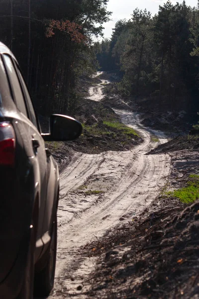 Ağaçlar ve tepeler arasından geçen kumlu toprak bir yol.