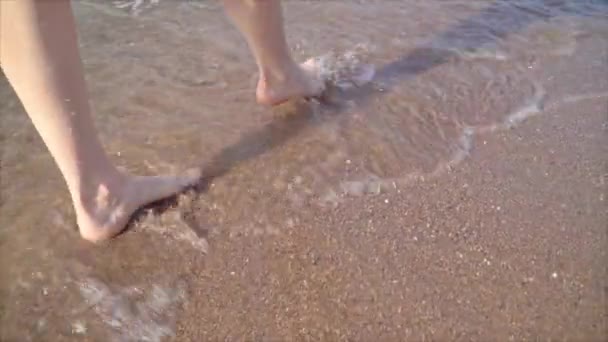 Piedi di una ragazza che cammina sulla spiaggia. Tesoro sulla spiaggia. primo piano delle gambe. stock video — Video Stock